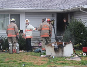 Firefighters inspect a residence on W. Crawford Avenue for damage after a doghouse caught fire Wednesday morning.